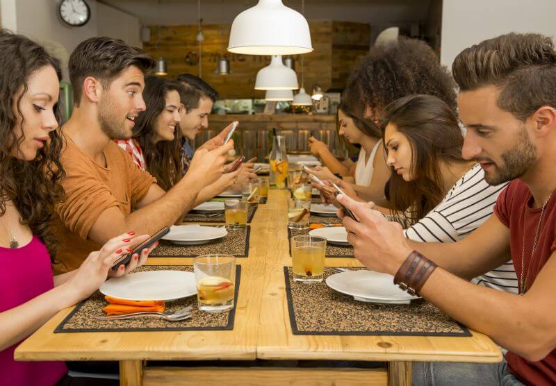 Alle am Tisch tippen nur auf ihren Smartphones und achten nicht aufeinander